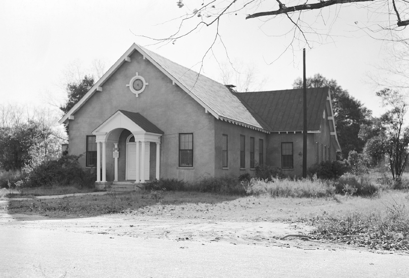 A picture of a church on a dirt road from the 1950's.