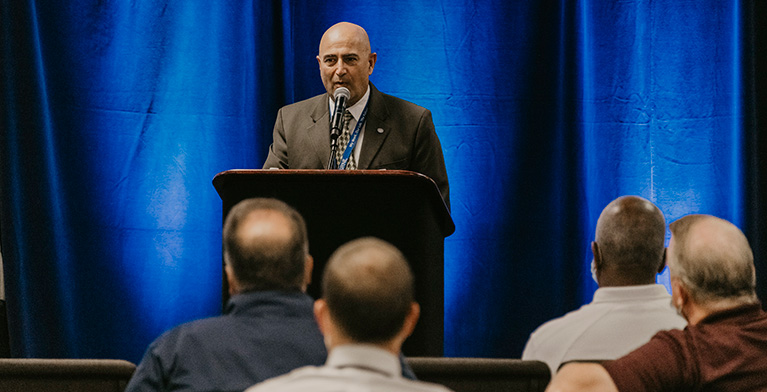 Lab Director Vahid Majidi addressing an audience from a podium